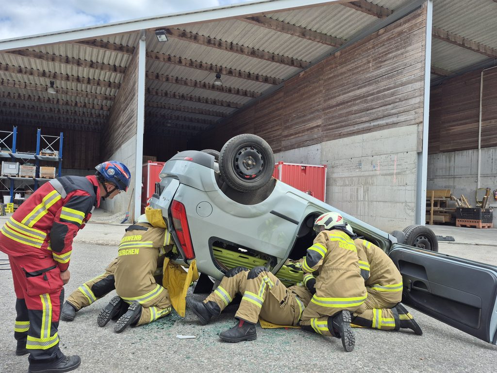 Feuerwehrleute bei einer Rettungsübung mit einem umgekippten Auto in einem Lagerhaus